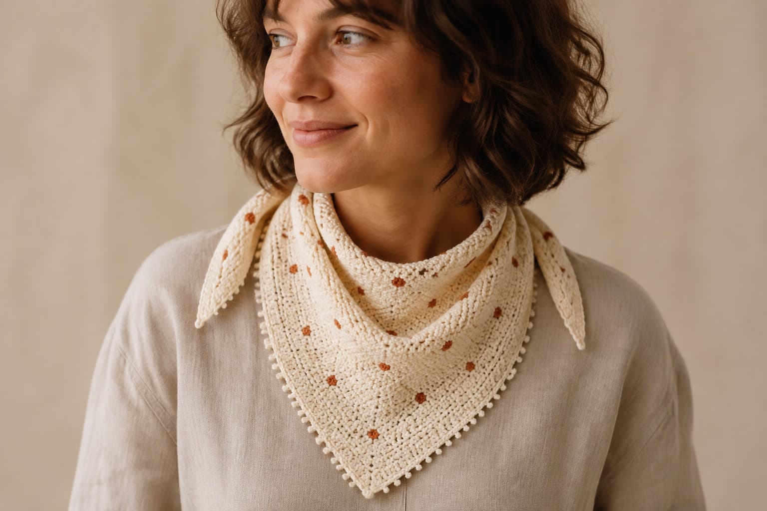 Adult wearing a cream crochet bandana with small terracotta tapestry dots